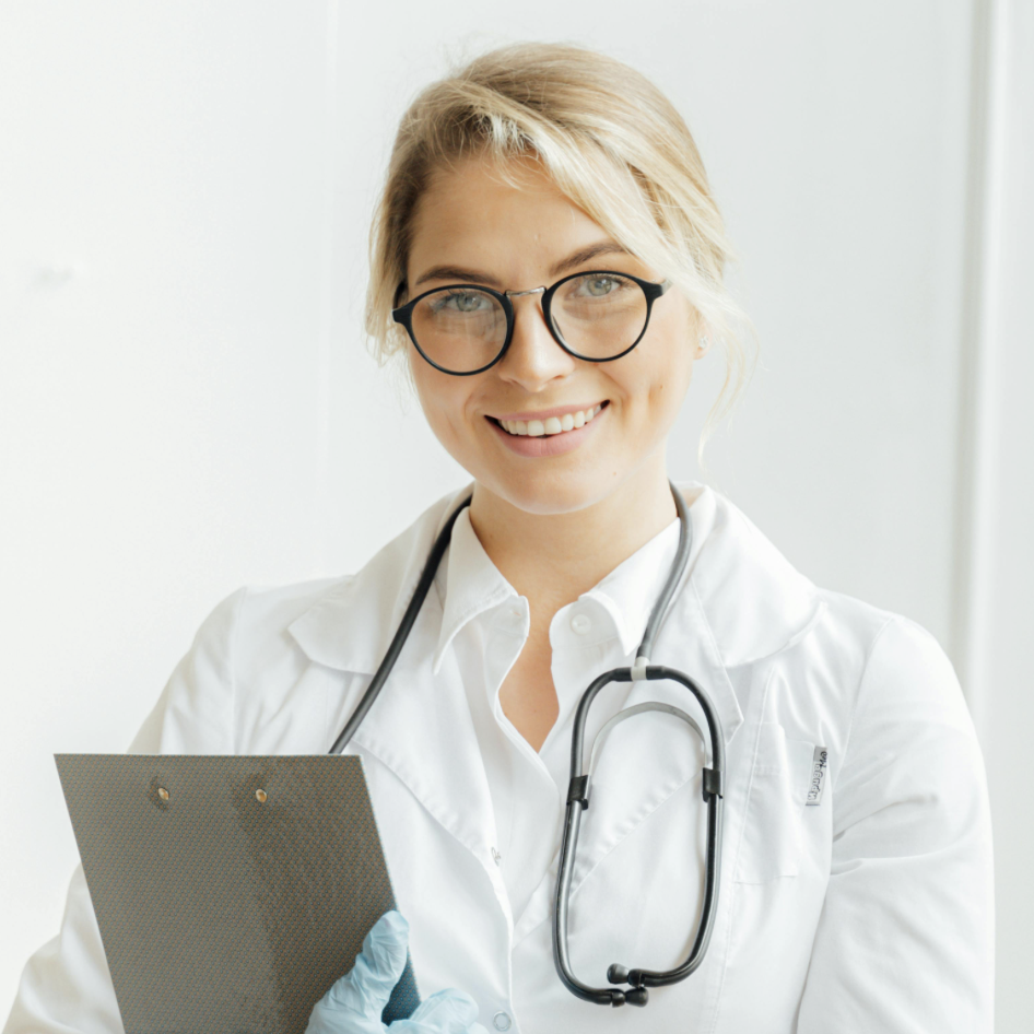 Female clinician wearing glasses and a stethoscope, smiling while holding a clipboard