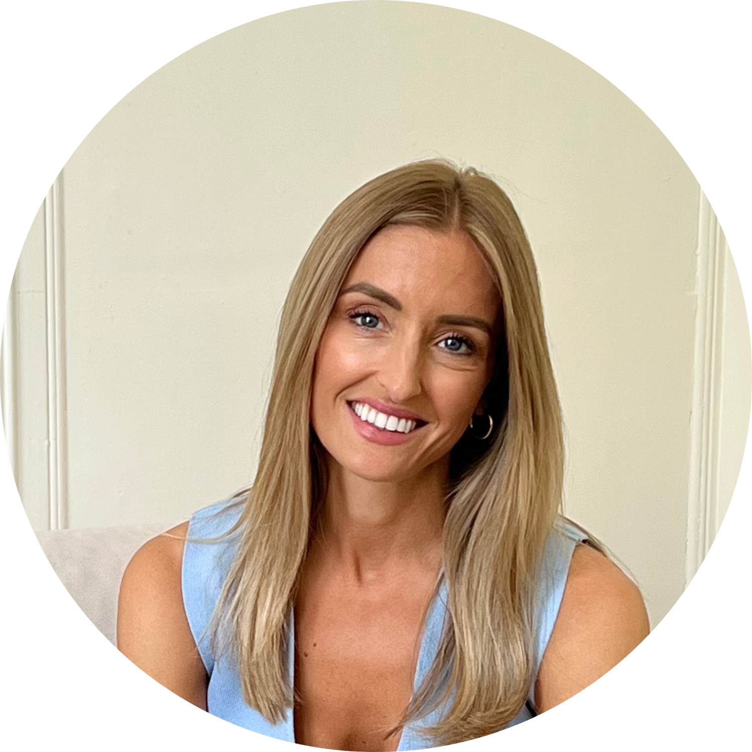 Smiling woman with shoulder-length blonde hair in a sleeveless light-blue top, circular portrait